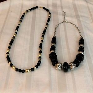 Set of two necklaces, one in black and silver and one in black and gold.